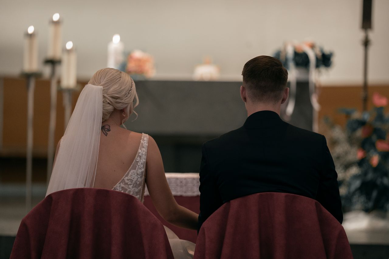 A couple sitting in a church during their wedding ceremony, showcasing love and commitment.